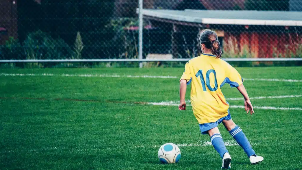 Teenage girl playing football on a stadium field, representing DB Sports Tours' youth and girls' soccer tour to Brazil
